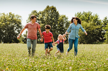 Young family running hand in hand through a field