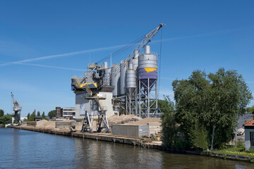 Bulk-handling crane unloading sand, road metal and gravel from cargo vessel ship