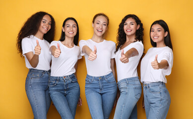 Obraz premium Multiethnic Women Gesturing Thumbs-Up Smiling To Camera Standing In Studio