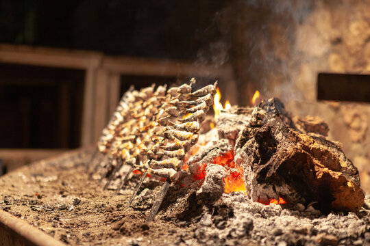 Un fuego con brasas y unos pinchos de espetos de Malaga