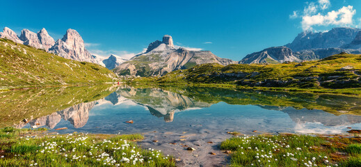 Fototapeta na wymiar Awesome alpine highlands in sunny day. Wonderful Mountain Landscape with perfect blue sky in Dolomites Alps. Mountain landscape, mountain range reflected in calm water. panorama. Picture of wild area
