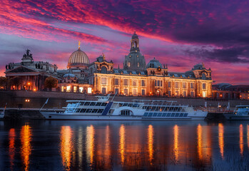 Fototapeta premium Fantastic colorful sunset in Dresden with dramatic sky, over the Elbe river. Old Town glowing in lighten reflected in calm water. Picturesque unusual scene. Creative image. Famouse Dresden buildings