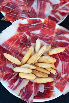 A plate of iberic ham with a few breadsticks
