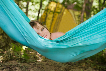 a smiling child girl lies in a hammock on a summer day. Summer vacation 