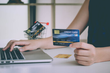 Hands holding a credit card, typing on the keyboard of laptop, online shopping.