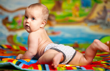 Funny plump caucasian six-month-old girl crawls on the floor