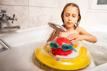 Funny little unidentified girl showering a head made of a ball