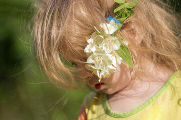 Naklejka premium Portrait of a little cute girl with a jasmine flower in her hair