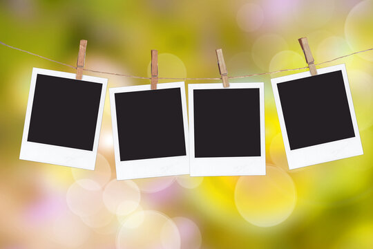 Four blank instant photo frames hanging on a rope, on green blur nature background