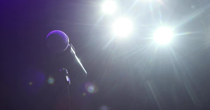 Musical instrument concept, vocal equipment. Professional concert microphone on stage for record or speak to audience in dark in the spotlight. Camera in motion.