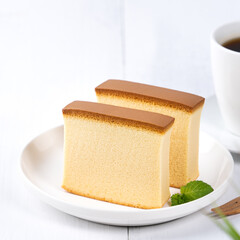 Castella (kasutera) - Beautiful delicious Japanese sliced sponge cake food on white plate over rustic white wooden table, close up, copy space design concept.