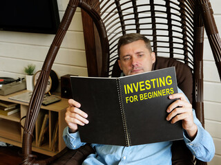 Man reads investing for beginners book at home.