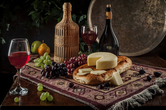 Fruit with red wine. Classic beautiful still life with a glass of red wine and fruit on an old vintage wooden dark table. Concrete background. Dramatic light. Rustic style. Candles in the candlestick