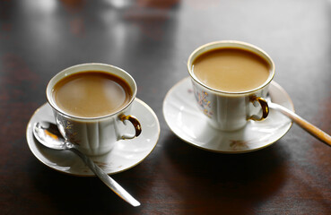 two tiny coffee cup with hot milk coffee and teaspoons