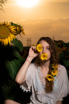 Beautiful young girl posing in a sunflower field at sunset 