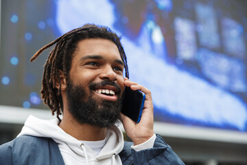Image of african american man smiling and talking on mobile phone