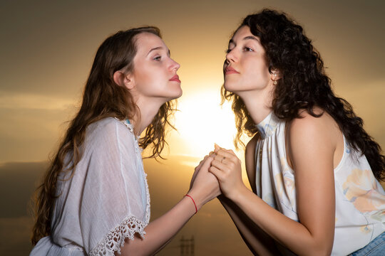 Beautiful young girls posing together at sunset in a sunflower field
