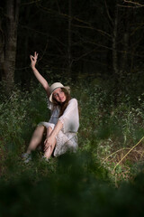 Beautiful young girl with a straw hat posing in a dark forest