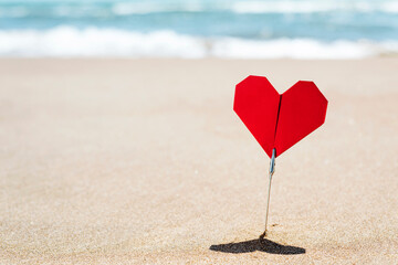 red origami heart on the beach with blank space