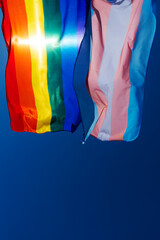 gay and transgender pride flags waving on the sky