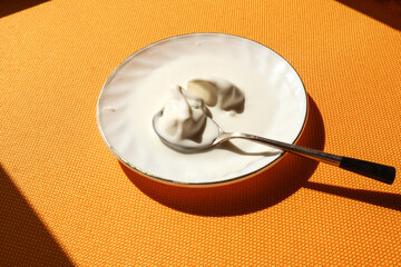 Saucer with ice cream and a teaspoon on a yellow background, top view, close-up, place for the inscription