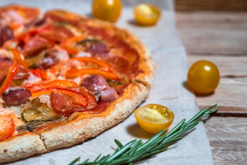 Appetizing pizza on a wooden table surrounded by herbs and spices. The concept of delicious food, restaurants and cafes