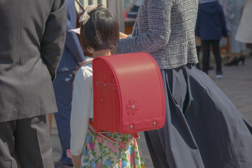 入学式に向かう赤いランドセルをしょった新一年生の女の子とその両親	
