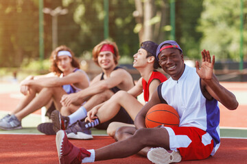 Happy African American basketballer and his multiracial team relaxing after match at outdoor stadium, free space