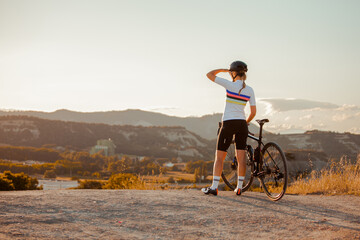 Fit young female cyclist, standing with her bike in hand, admiring the scenery.