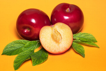 Plum fruit with plum leaf on a yellow background