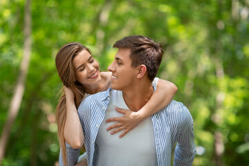 Obraz premium Millennial man holding his beautiful girl outside on sunny summer day