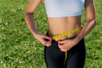 Happy slender girl holds a centimeter tape in her hands.