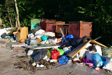 A large number of accumulated plastic bags and plastic packaging of household waste in garbage containers. The problem of garbage removal from the village, the concept of environmental pollution