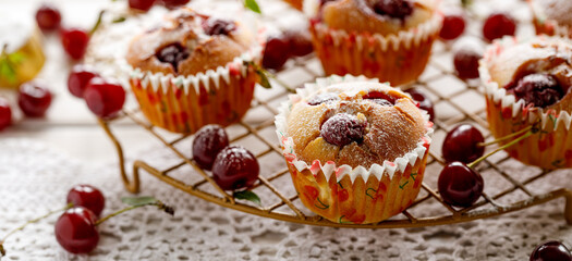 Homemade cherry muffins sprinkled with powdered sugar on a cooling tray close up view