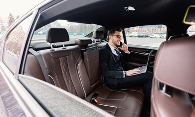 Young businessman talking on smart phone in luxury auto