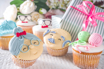 Grandparents Day holiday concept, Grandmother and Grandfather Day greeting background. Sweet homemade cupcakes for grandma and grandpa, with I love you Granny text inscription. With gifts and flowers