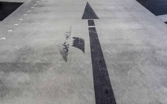 Closeup Of Black Left Turn And Straight Arrow Sign On An Old Small Road In Northern Europe