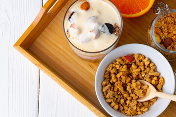 Tasty breakfast with granola, yoghurt and fruits in a glass bowl