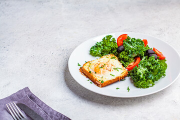 Baked egg and cheese toast with salad on a white plate.