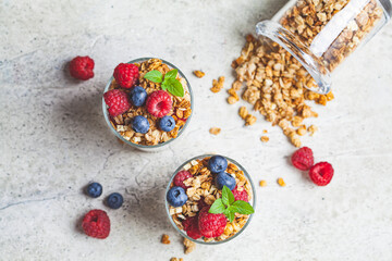 Obraz na płótnie Canvas Yogurt parfait with granola, raspberries and blueberries in glasses, copy space, top view. Healthy breakfast concept.