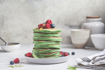 Matcha tea pancakes with berries and honey, white background. Healthy vegan food concept.