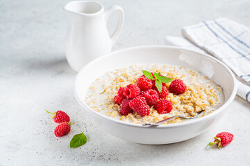 Breakfast oatmeal with raspberries in a white bowl. Healthy breakfast concept.