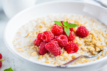 Breakfast oatmeal with raspberries in a white bowl. Healthy breakfast concept.