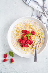 Breakfast oatmeal with raspberries in a white bowl, top view. Healthy breakfast concept.