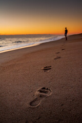 A person walking on the beach leaving footprints in the sand © RK