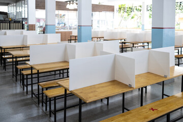 Corrugated plastic sheet partition on the tables in the cafeteria at school during its reopening,plastic shield as a barrier to prevention of infection,safety of students,social distancing,new normal