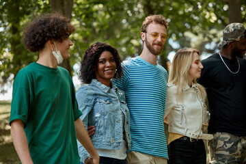 african and caucasian young people have rest together outdoors, smile and talk with each other, be friendly and tolerant