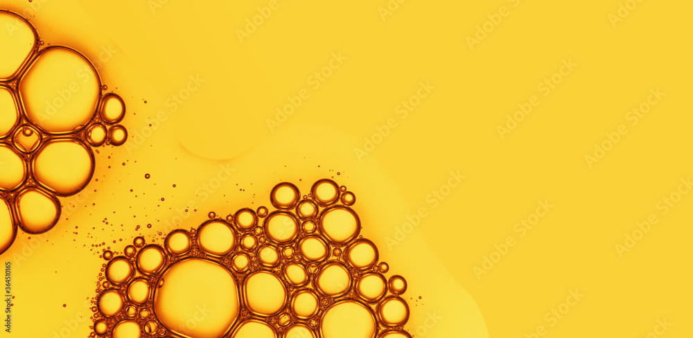 Wall mural oil drops with bubbles on yellow background. cosmetic oil serum detail. abstract orange color liquid