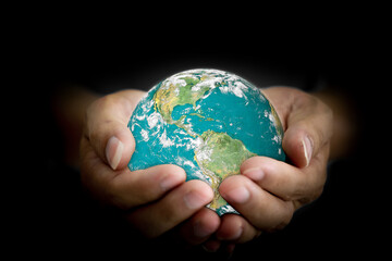 Environment concept. Earth with light in human hand on black background. Elements of this image furnished by NASA