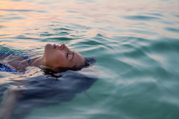 Woman swimming in the sea at sunset